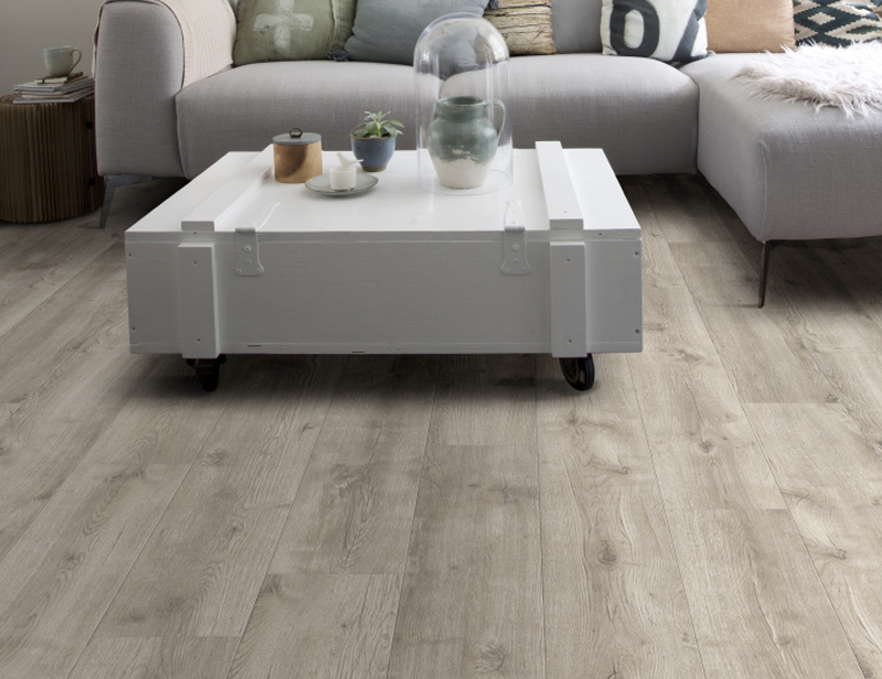 PVC vloer in een woonkamer met een L-bank en vierkante salontafel met accessoires.