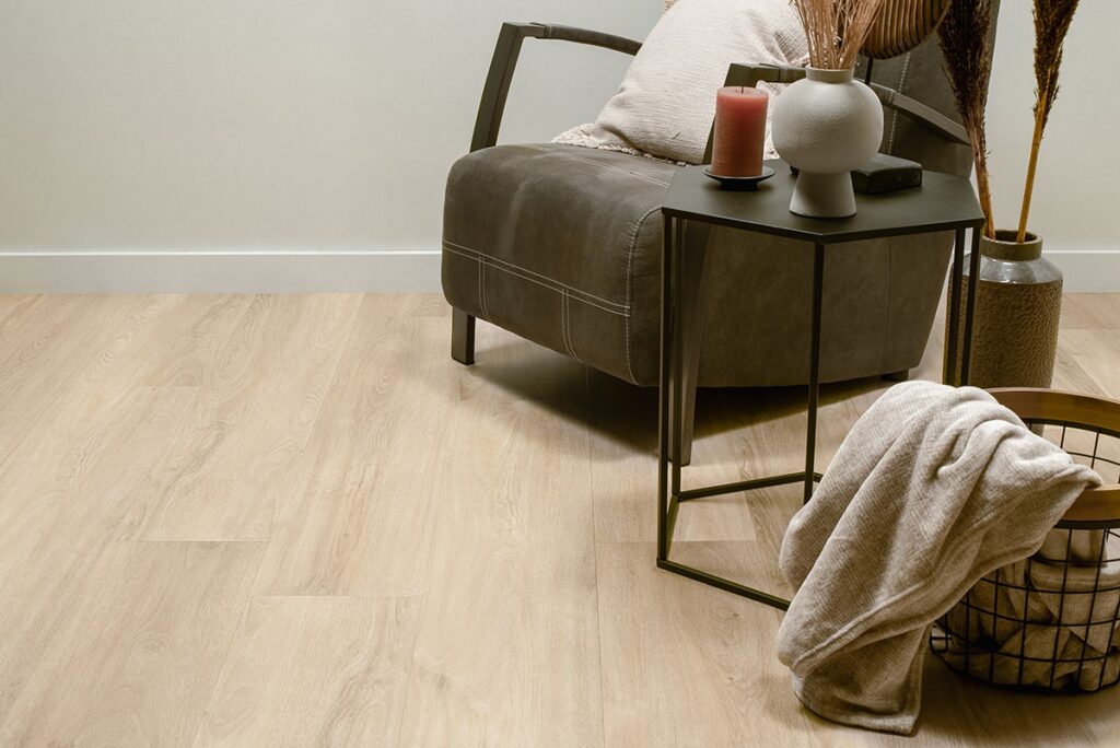 ALT: Lichte PVC vloer in een zithoek met een moderne stoel, bijzettafel en een mand met een deken.